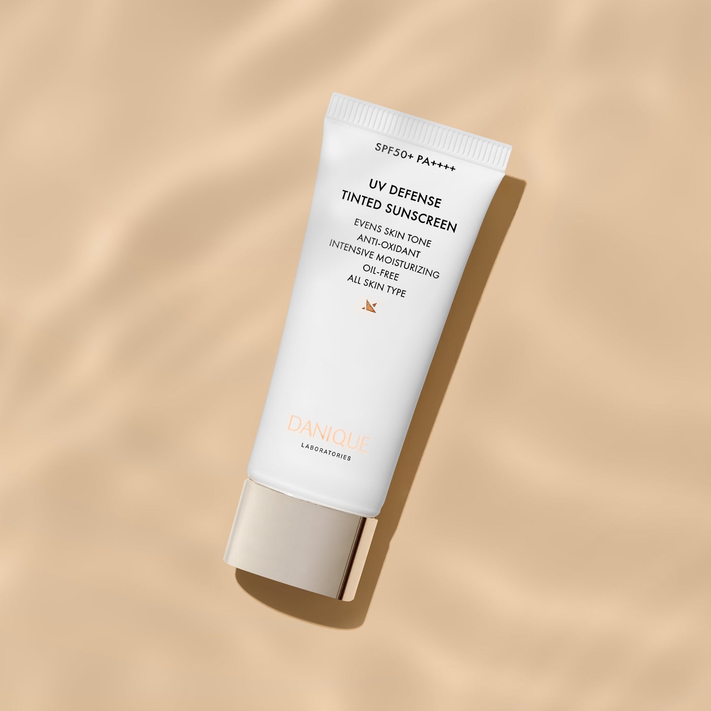 Tube of UV Defense Tinted Sunscreen on a beige background