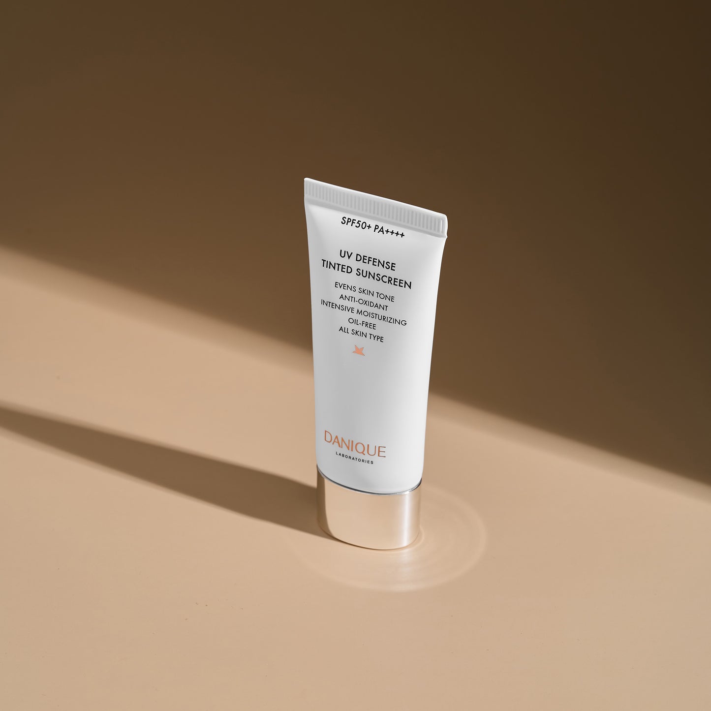Tube of Danique UV Defense Tinted Sunscreen on a beige background