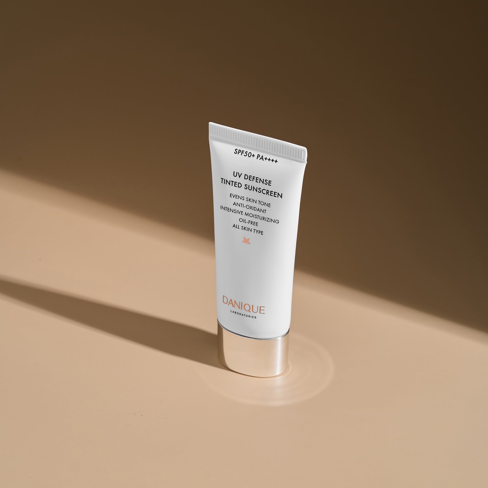 Tube of Danique UV Defense Tinted Sunscreen on a beige background