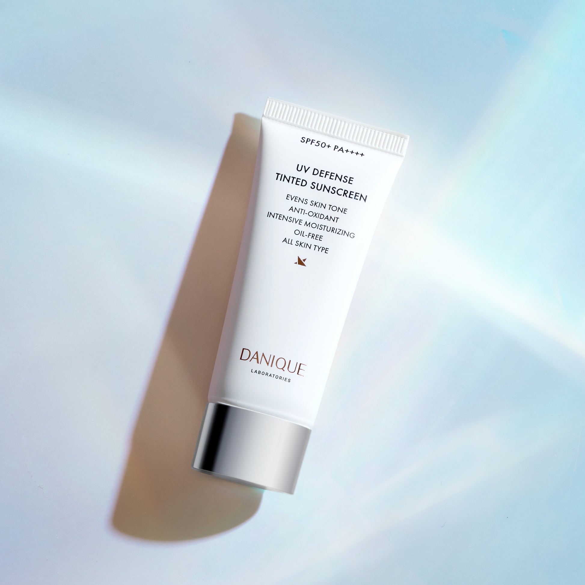 Tube of Danique UV Defense Tinted Sunscreen on a gradient background